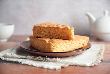 Delicious freshly baked sponge cake on a plate. Rustic background