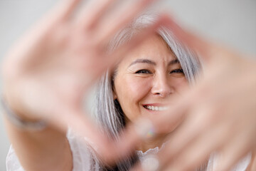 Emotional portraits of a paled long hair asian matured woman on grey background