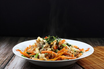 Spicy fried and stirred chopped fish meat, sliced carrot, fresh mushroom, chilly and basil on the plate. Famous traditional hot and spicy seafood menu in Asia restaurant. 