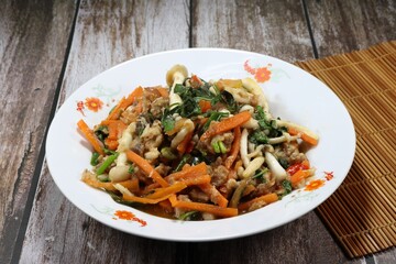 Spicy fried and stirred chopped fish meat, sliced carrot, fresh mushroom, chilly and basil on the plate. Famous traditional hot and spicy seafood menu in Asia restaurant. 