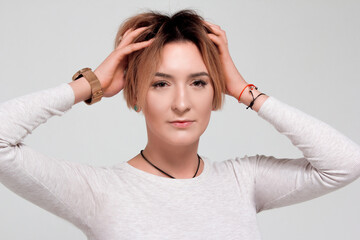 Portrait of a young woman with short hair. In a white sweater and green trousers. On white background.