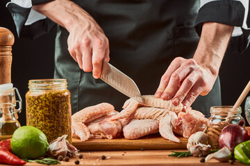 Men cutting raw chicken meat, preparing ingredients for a dinner dish