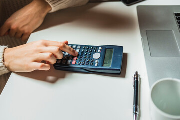 Close-up of business woman hand using calculator to calculate business data at home office.
