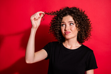 Close-up portrait of pretty disappointed wavy-haired girl touching unhealthy hair damage loss isolated over bright red color background