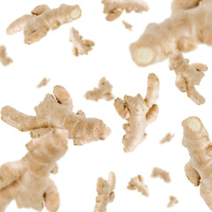 Many ginger roots free falling on white background. Selective focus - shallow depth of field.