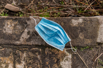 A used dirty disposable mask lays on the street and causes danger for ecology
