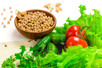 Chickpea beans in wooden bowl. fresh tomatoes, cucumbers, lettuce salad on tablecloth isolated on white background. Organic, healthy food concept