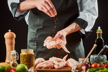 Chef sprinkles grounded chili onto a chicken wing