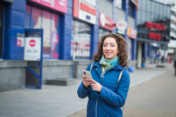 Beautiful girl stands on the street and holds a mobile