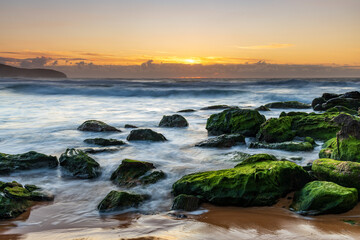 Sunrise seascape with light cloud, waves and rocks