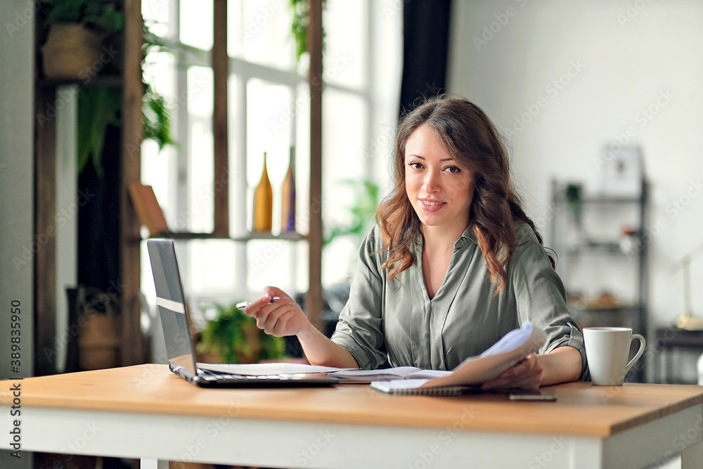 Wall mural young woman working from home office. freelancer using laptop and the internet. workplace in living 