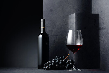 Fototapeta na wymiar Red wine and blue grapes on a black stone table.