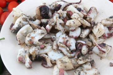 cooked octopus tentacles as sea food with tomatoes and peppers background