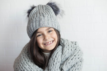 happy laughing child girl in winter knitted hat and scarf hat at studio