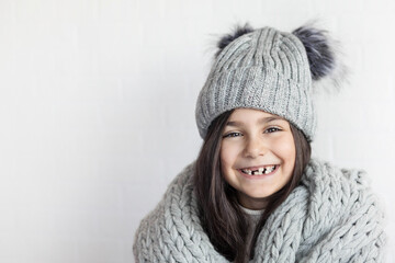 happy laughing child girl in winter knitted hat and scarf hat at studio