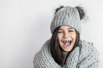 happy laughing child girl in winter knitted hat and scarf hat at studio