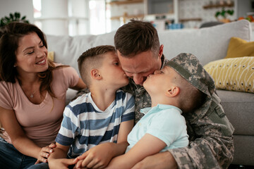 Obraz premium Happy soldier sitting on the floor with his family. Soldier and his wife enjoying at home with children