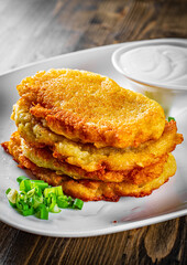 potato pancakes with sour cream in a plate on wooden table