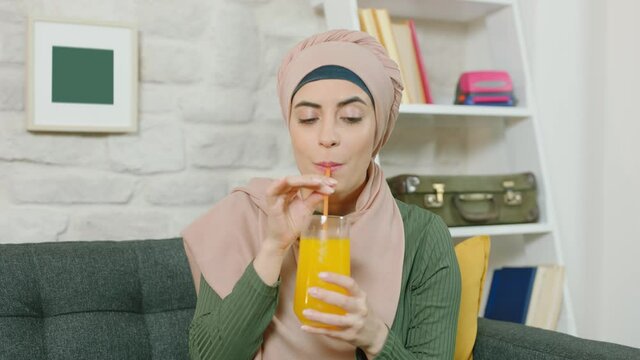 Young muslim woman drinks yellow Cola In home.Slow motion video.