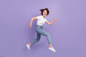 Full length body size side profile photo of young woman jumping high running laughing smiling isolated on bright purple color background