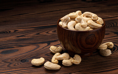 Cashew nuts in wooden bowl on black background