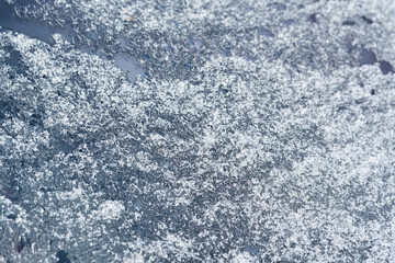 Melting snow on the car window. Close-up of ice crystals.