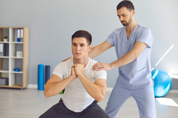 Physiotherapist helping young athlete do squats during rehabilitation therapy after sports injury