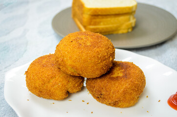 Three Chicken Bread Cutlets on top of each other with Bread slices in the background