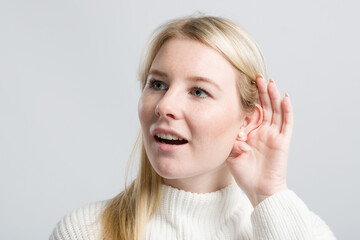 Young woman with hand at her ear tries to listen better