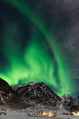 Spectacular dancing green strong northern lights over the famous round sand beach near Haukland on...