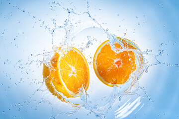 Fototapeta na wymiar Two halves of orange fruit splashing into clear water.