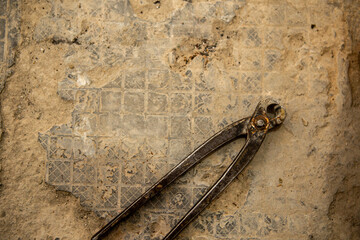 Renovation of the bathroom and installation of new ceramic tiles is in progress. Focus on the steel masonry pliers that are on the floor.