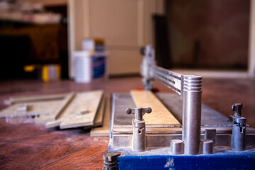 The house is being renovated. The tile cutter is located on the floor. A few moments ago, a worker used it to cut a ceramic tile.