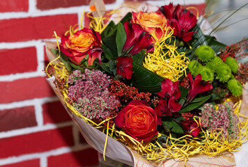 autumn bouquet with red, orange flowers, on the counter of a flower shop, against a background of a...