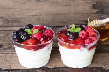 Fruit yogurt has strawberry raspberry blueberry canberry and honey greek white clean In bowl on a wooden background from top view.
