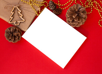 mock up poster on red table surrounded by pine cones and new year christmas attributes