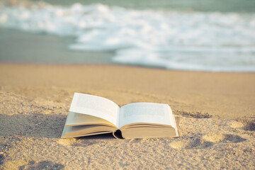 Open the book on the beach
On the outdoor blurred sea background