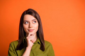 Photo of minded young lady finger chin look up empty space wear green shirt isolated orange color background