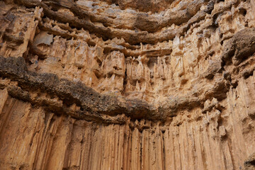 Close up to the light brown stone ancient natural corroded wall up in the mountain, with the abstract curve pattern