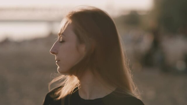 Face of young beautiful woman on the beach during amazing sunset who is turing right.