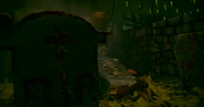 Halloween traditional holiday. Glowing lanterns in the fog pieces of people in smoke. Coffins with skeletons torn legs and arms scattered on the ground in autumn of large leaves of trees.