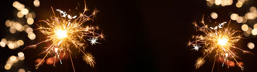 Silvester / New Year background banner panorama long- sparkling sparklers and bokeh lights at dark night by a Silvester party
