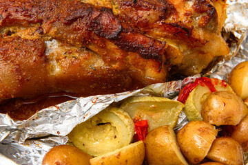 baked meat and potatoes on a baking sheet, pork knuckle delicious food