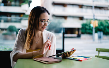 Young female freelancer with tablet and notes in cafe outdoor