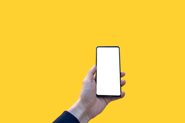 Isolated hand holding a mobile telephone with a yellow background