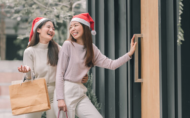 Two women doing window shopping and holding bags in christmas season