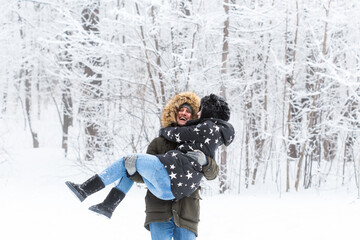 Young couple have fun in a snowy park. Winter season.