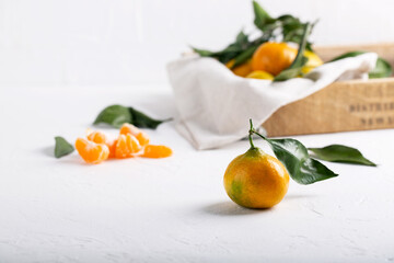 Tangerine clementine, mandarin, citrus fruit with green leaf on white table.