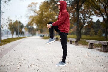 Fototapeta premium Athletic sporty man training in hoodie sweatshirt in urban city park.