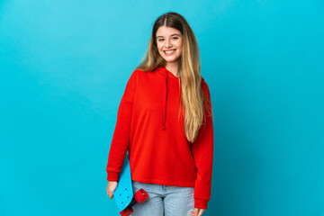 Young blonde woman isolated on blue background with a skate